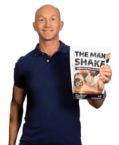 Smiling bald man in a navy polo shirt holds a book titled 'The Man Shaker' about health and fitness.