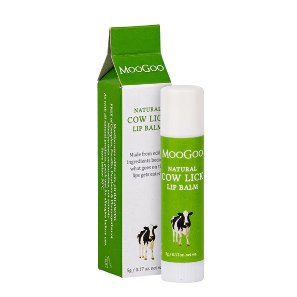 MG-BodyCare-LipBalm-CowLick-1_efec29e7-aaf2-4b92-b195-95a118393d44_1920x Lip balm tube with green label and white cap beside its green-and-white MooGoo packaging, featuring a cow illustration on the label.