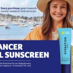 Cancer Council sunscreen promotion banner with a smiling woman by a marina and sunscreen products on the right by the water.