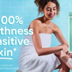 Gillette Venus advertisement: woman in a towel shaving her leg, with razor pack and two razors on the right; slogan 'Up to 100% Smoothness for Sensitive Skin'.